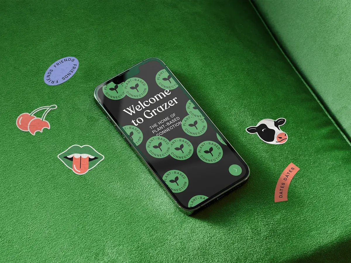 The new-look Grazer app on a phone, on a green velvet sofa with Grazer stickers